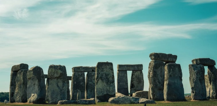 A close panorama of the Stonehenge sarsens and lintels against a pale sky