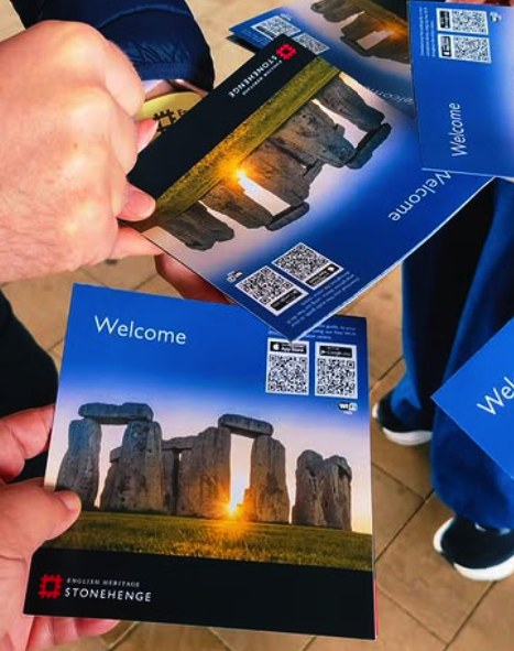 Visitors holding English Heritage welcome leaflets outside the Stonehenge visitor centre